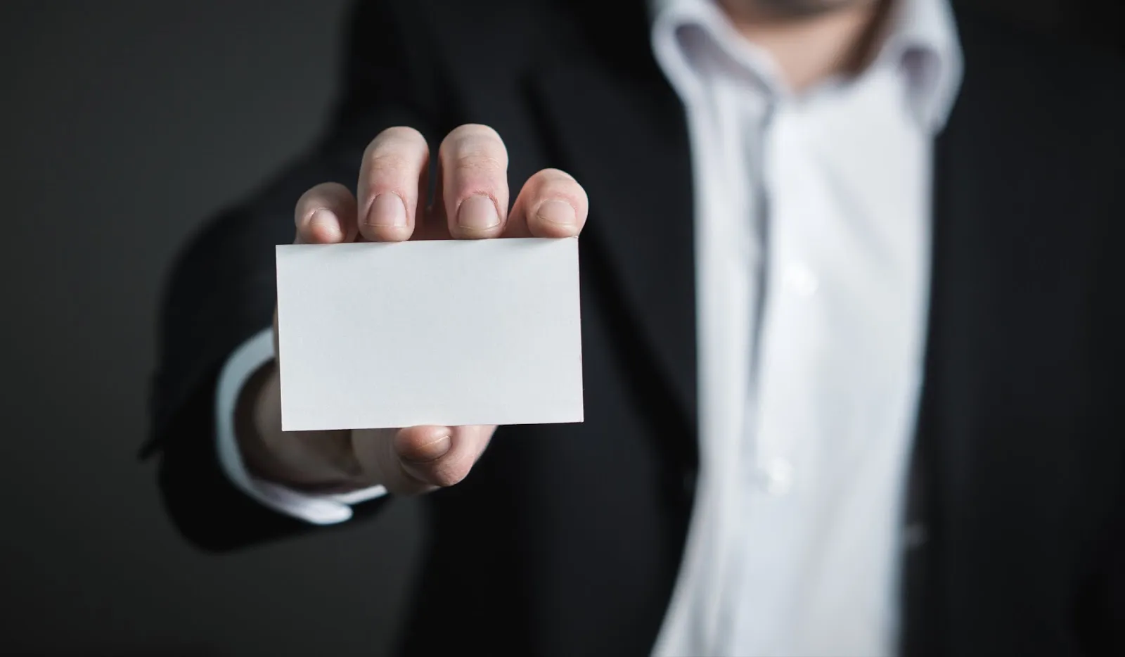 Salesperson in a suit holding out a blank business card